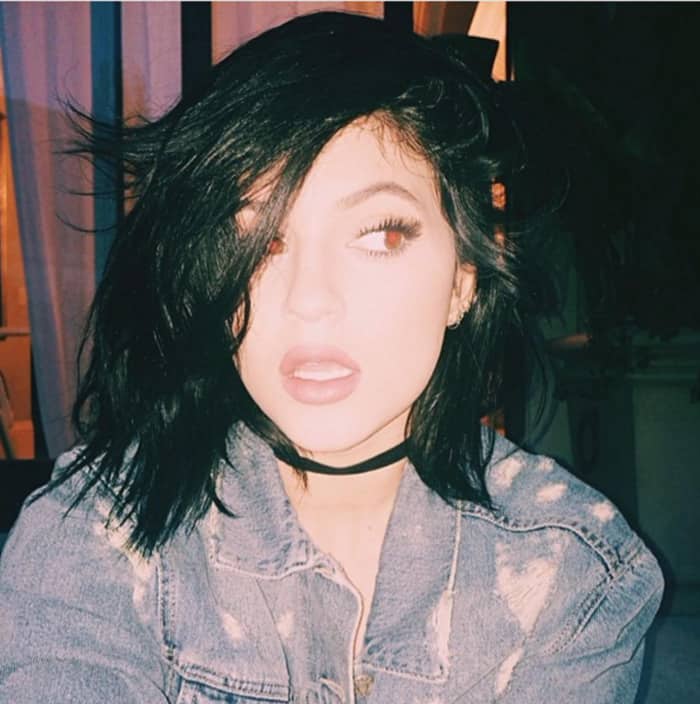 Kylie Jenner channels an edgy vibe with her tousled hair, distressed denim jacket, and signature choker