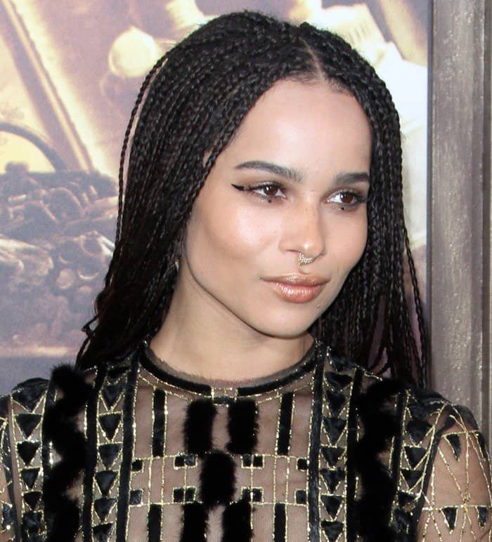 Zoë Kravitz exudes confidence with her striking septum ring and flawless makeup, perfectly complementing her braided hair and intricate gown for an effortlessly bold red carpet look