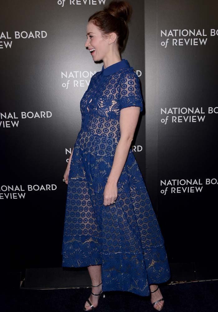 Emily Blunt laughs and shows off the floral pattern of her blue Elie Saab dress