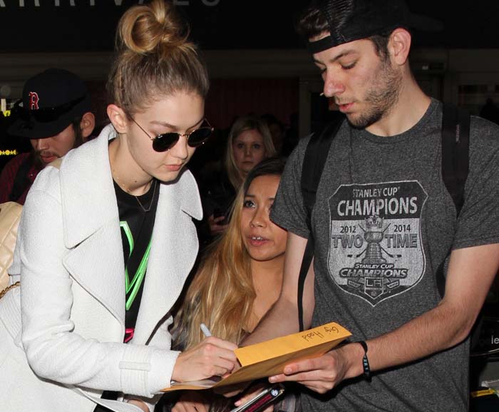 Gigi Hadid signs autographs for fans as she arrives at LAX