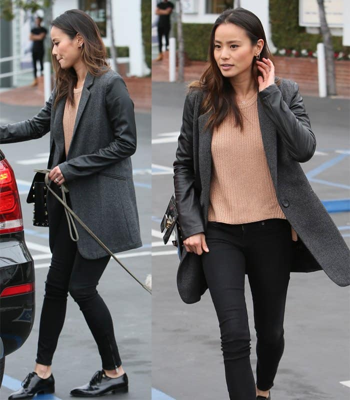 Jamie Chung pairs a knitted top with a leather-sleeved blazer, skinny jeans, sleek leather oxfords, and her hair styled effortlessly for a chic, casual look