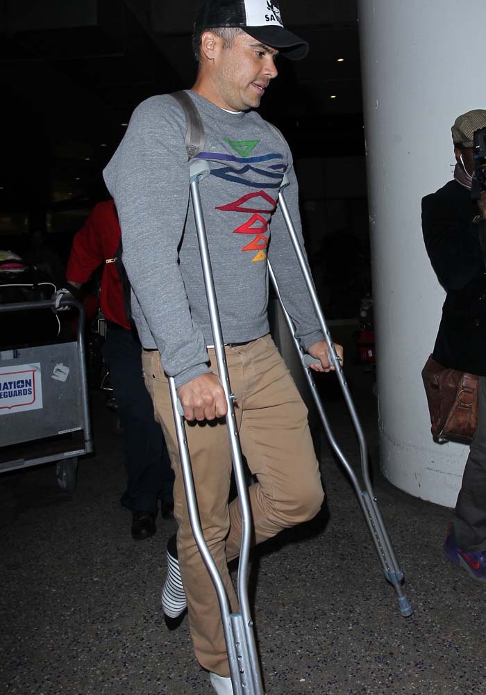 Jessica Alba's husband, Cash Warren, enters LAX on crutches