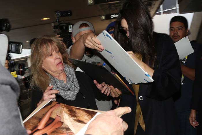 Kendall Jenner signs autographs for fans as she arrives at LAX
