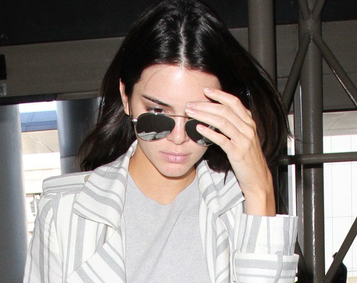 Kendall Jenner covers her face with her hand as she arrives at LAX