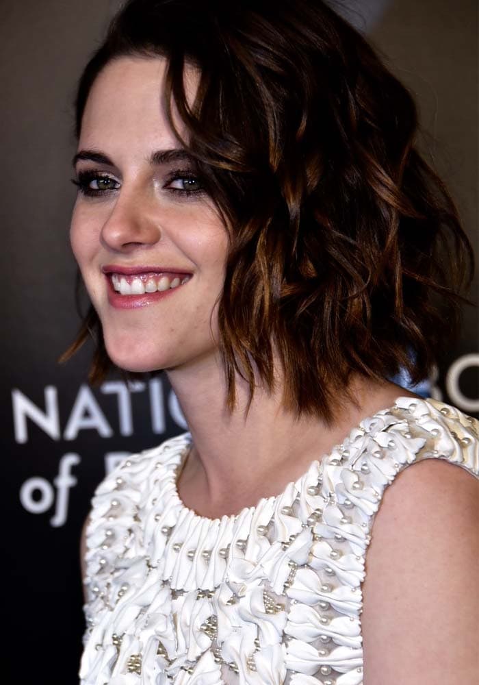 Kristen Stewart smiles in a white-and-pearl-embellished Karl Lagerfeld dress