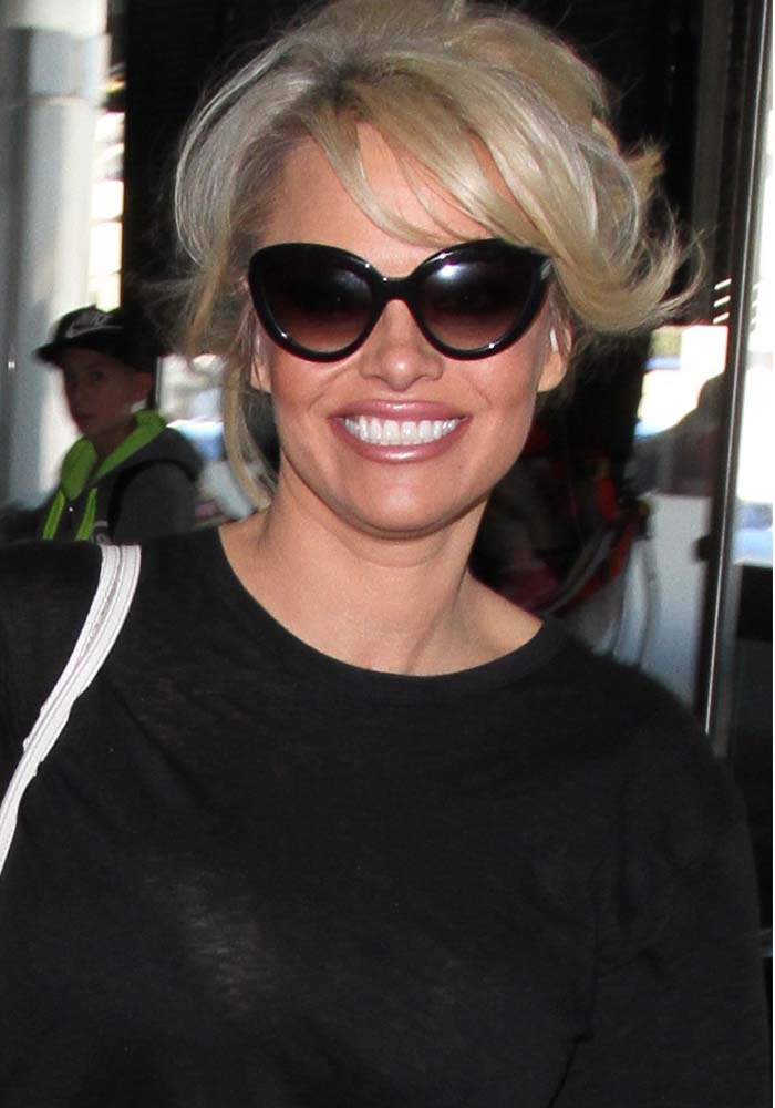 Pamela Anderson wears her blonde hair back as she departs from Los Angeles International Airport