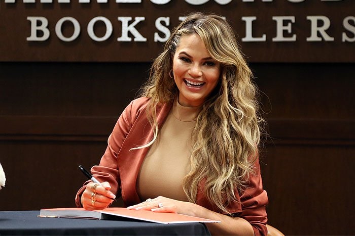 Chrissy Teigen shows off her Le Vian rings as she signs copies of her cookbook