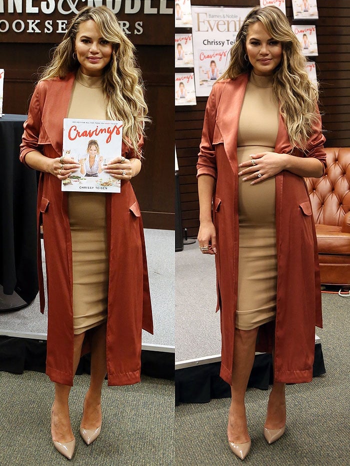 Chrissy Teigen holds a copy of her new cookbook and her growing baby bump