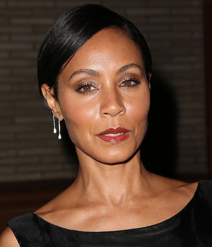 Jada Pinkett-Smith wears red lipstick and crystal earrings with her black dress