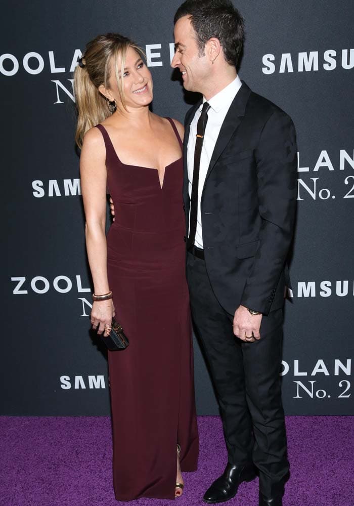Jennifer Aniston and then-husband Justin Theroux share a sweet moment on the purple carpet at the Zoolander No. 2 premiere, both dressed in coordinated eveningwear