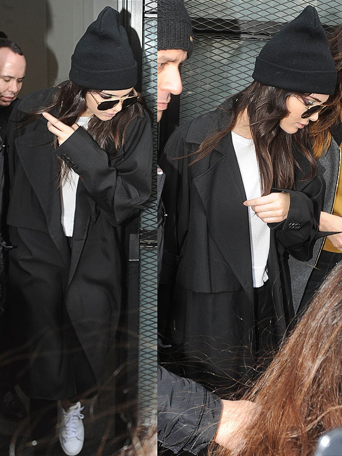 Kendall Jenner wears a monochrome look including a beanie and aviators as she moves between Fendi and Versace fashion shows