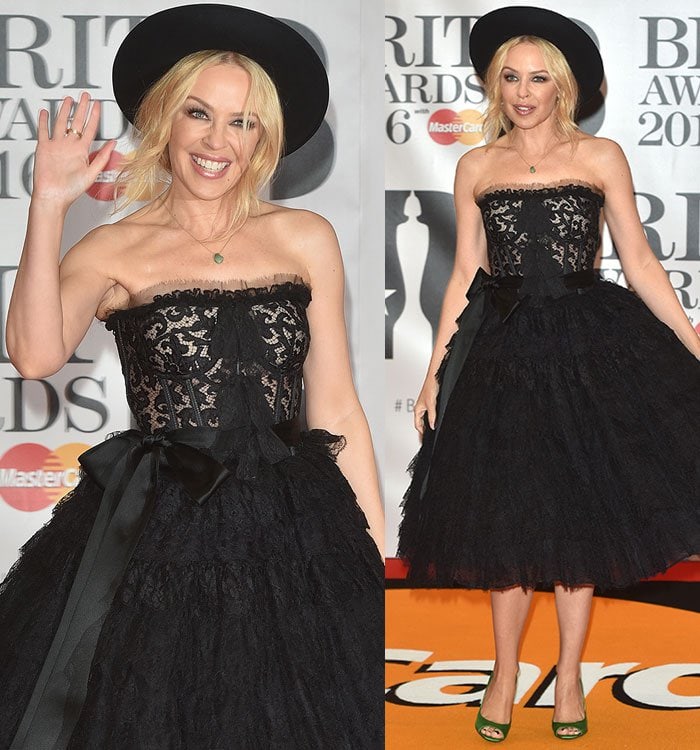Kylie Minogue channels vintage glamour in a strapless black lace Dolce & Gabbana dress, complete with a cinched waist bow and a voluminous tiered skirt, adding a modern twist with a playful wide-brimmed hat