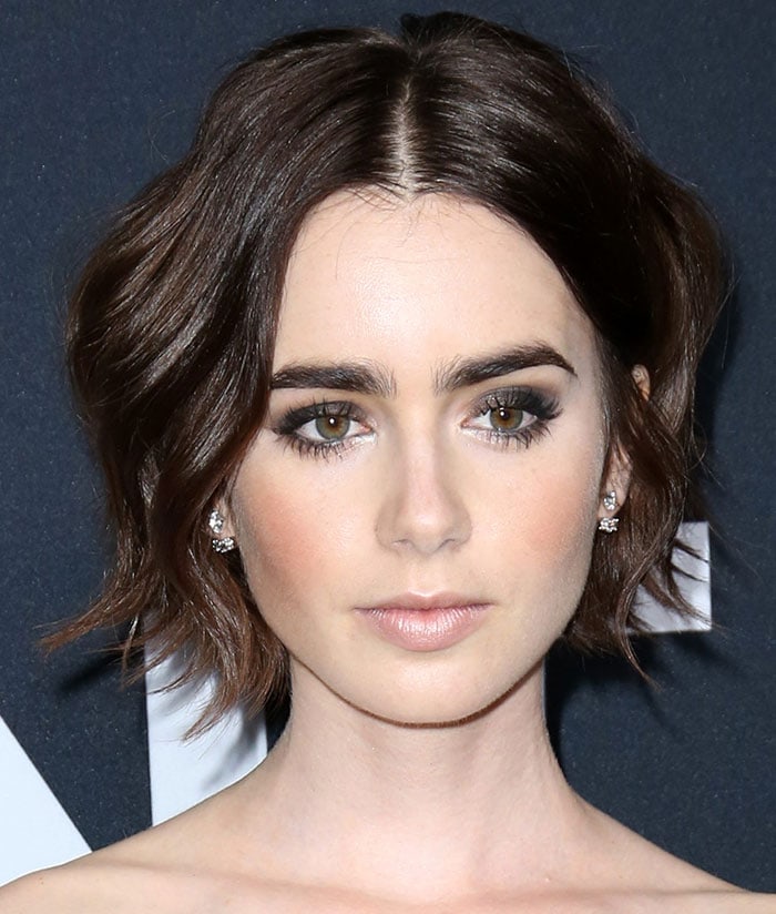 Lily Collins wore her brunette tresses in waves and sported smokey shadow and bold eyebrows