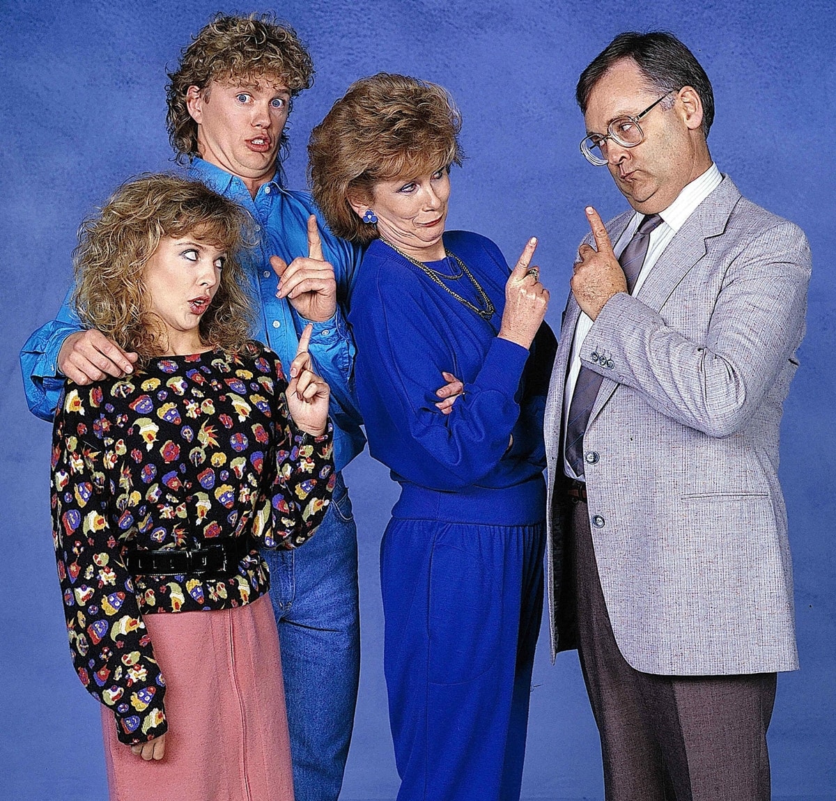 Kylie Minogue (left) in a playful cast photo from Neighbours, where she starred as Charlene Robinson, alongside Craig McLachlan, Anne Charleston, and Ian Smith