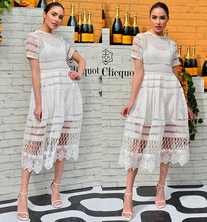Olivia Culpo poses at a Veuve Clicquot event in a white patterned dress