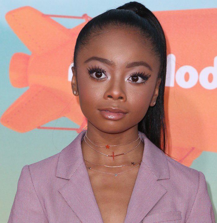 Skai Jackson sports a sleek high ponytail and layers delicate cross necklaces