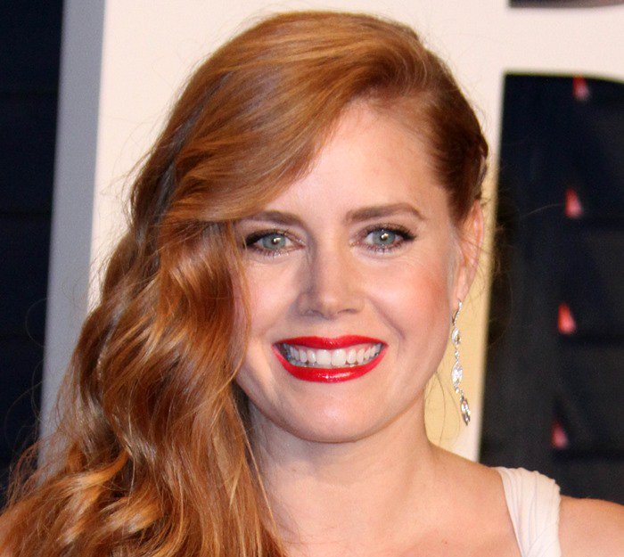 Amy Adams radiates elegance in a side-swept hairstyle and vibrant red lipstick, perfectly complementing her chic look at the 2016 Vanity Fair Oscar Party