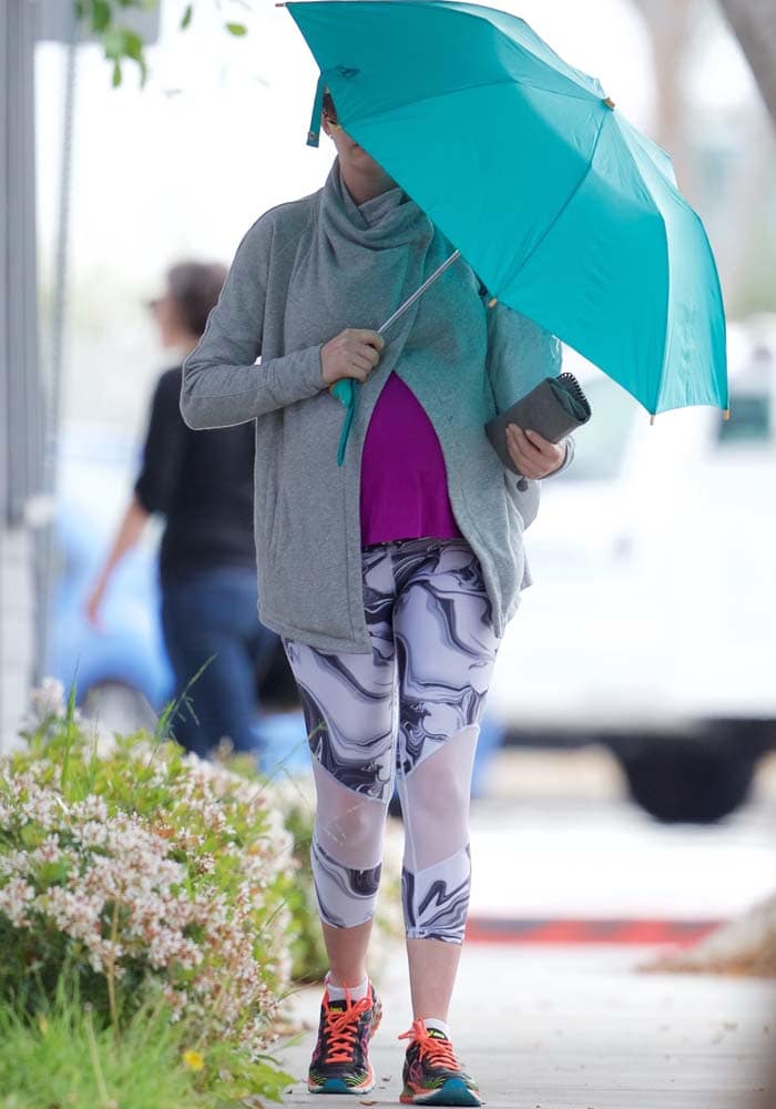 Anne Hathaway hides behind an umbrella as she leaves the gym