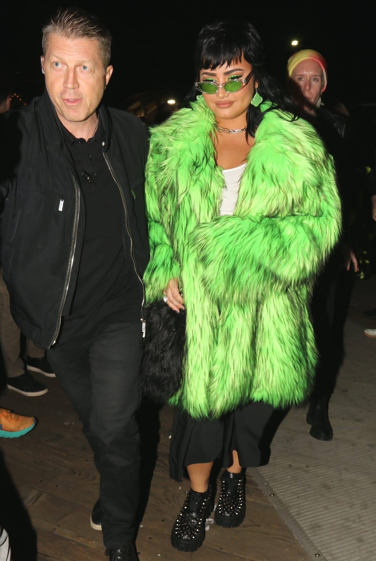 Demi Lovato in a green fur coat and studded booties arrives to celebrate Paris Hilton and Carter Reum‘s wedding