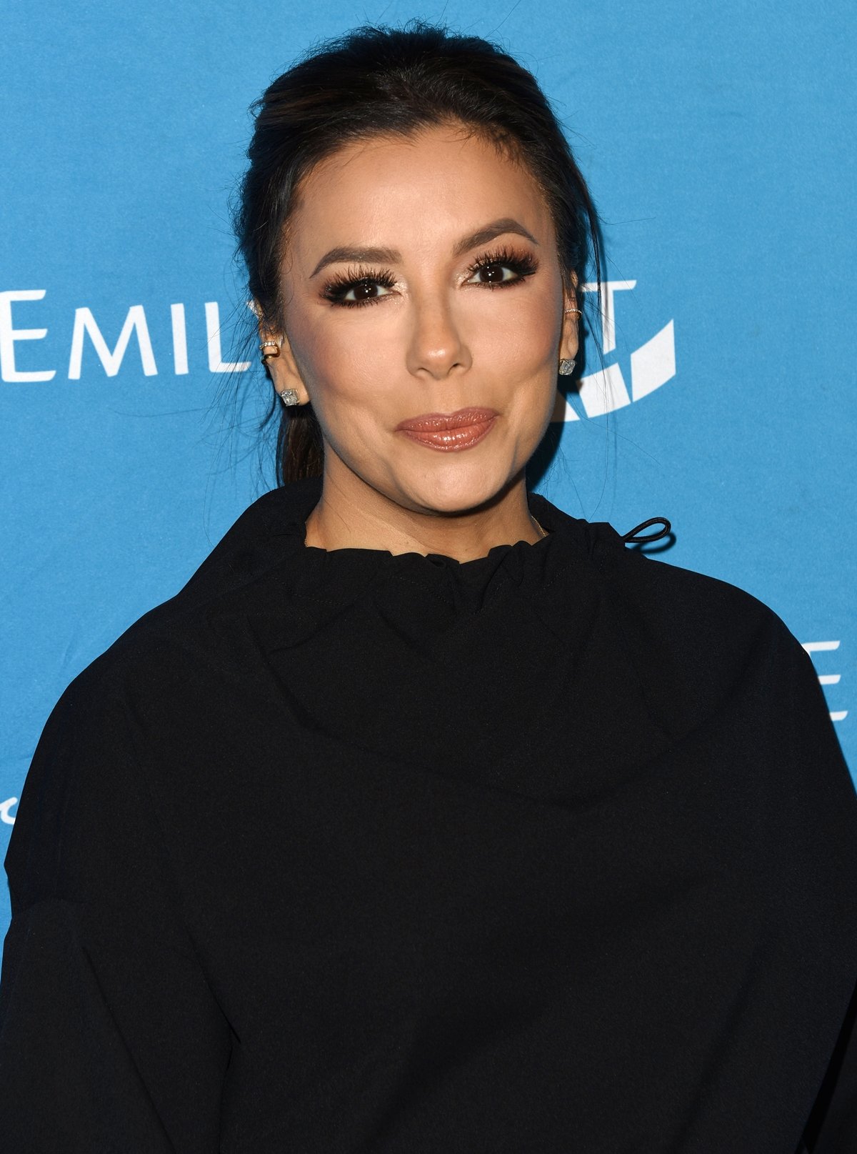 Eva Longoria stuns in a sleek black outfit at a red carpet event, showcasing her radiant makeup and elegant style