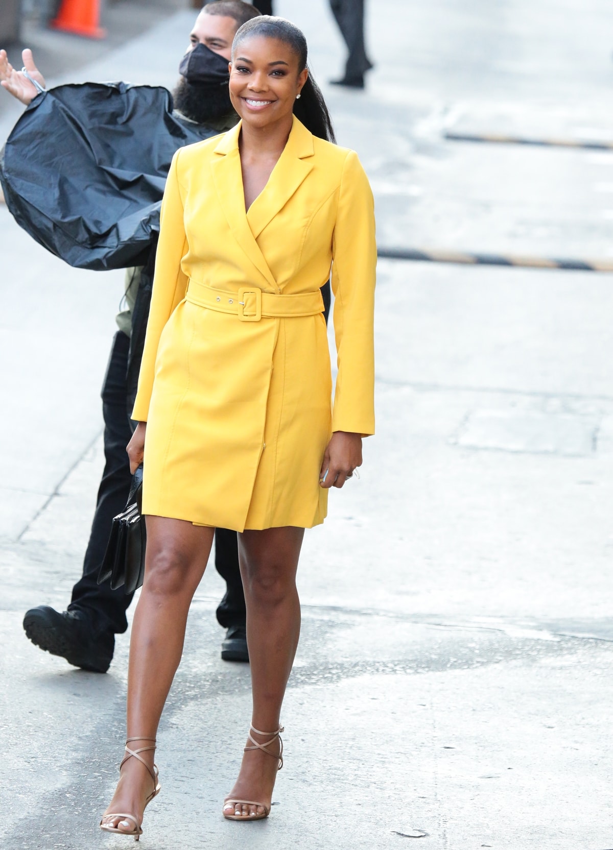 Gabrielle Union flaunts her legs in a yellow trench coat and ankle-strap heels