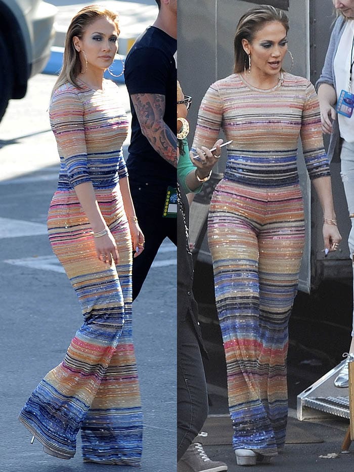 The jumpsuit features horizontal stripes in an array of vibrant colors, including shades of orange, blue, pink, red, and gold