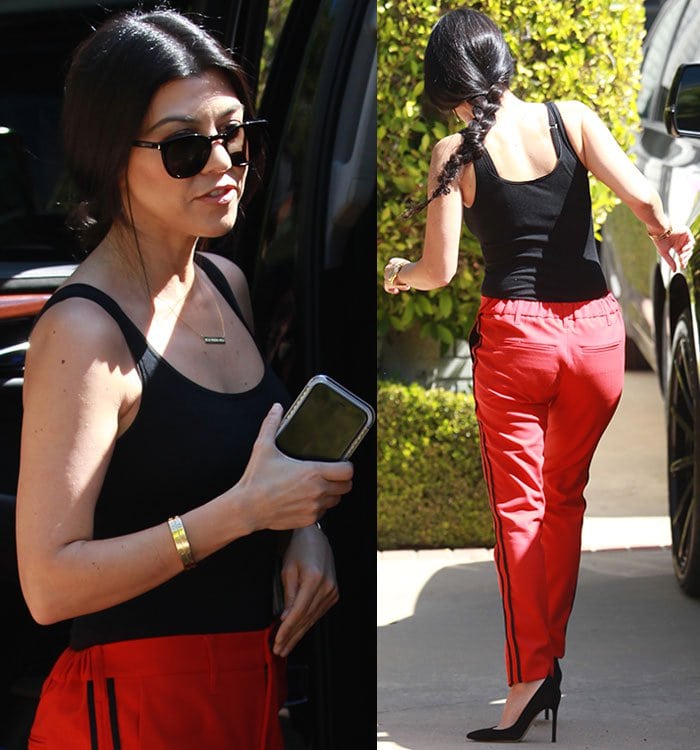 Kourtney Kardashian tucks a black tank top into a pair of red Zadig & Voltaire pants