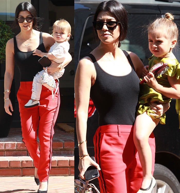 Kourtney Kardashian carries Penelope and Reign to a waiting car