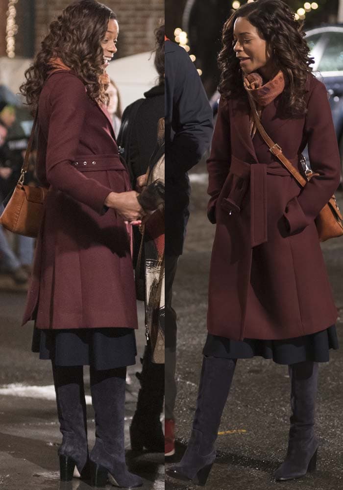 Naomie Harris wears a maroon coat overtop of a black dress while filming in Brooklyn