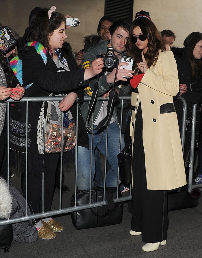 Selena Gomez poses for photos with fans in a Louis Vuitton coat