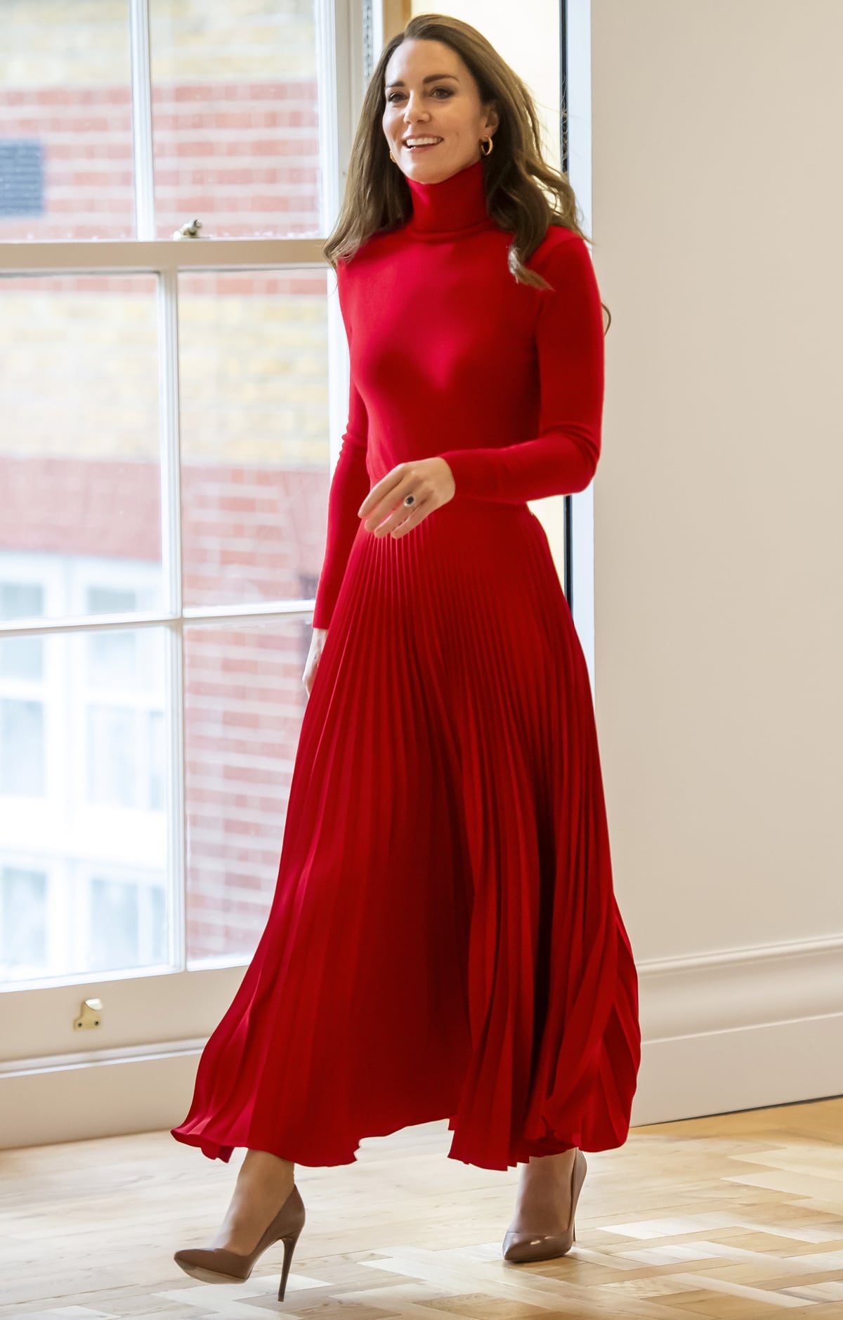 The Duchess of Cambridge wore a red turtleneck sweater from Ralph Lauren with a pleated skirt from Christopher Kane