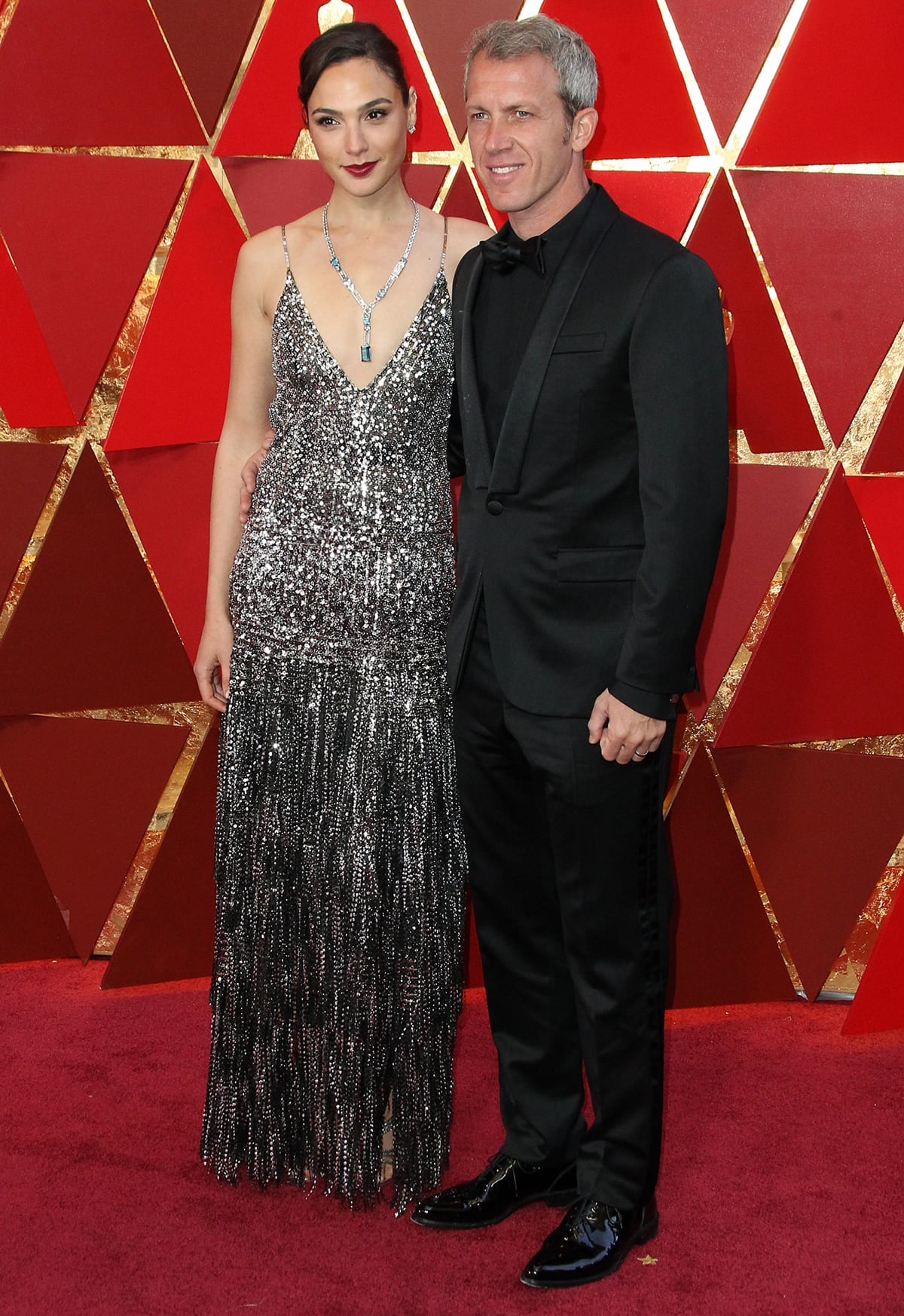 Gal Gadot wears a Givenchy dress and stunning Tiffany & Co. diamond necklace on the red carpet with her husband Yaron Varsano at the 2018 Academy Awards