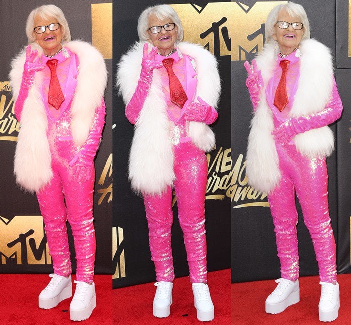 Helen Ruth Van Winkle, aka Baddie Winkle, wears a sparkling pink jumpsuit with a red tie on the red carpet