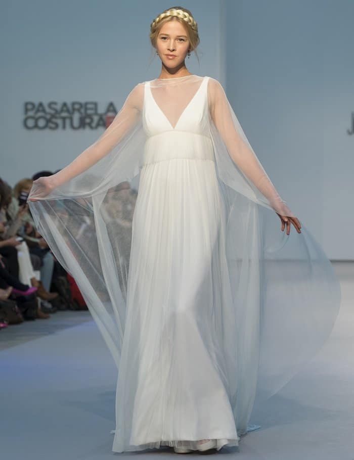 A model presents a flowing white gown with sheer cape sleeves for bridal designer Rubén Perlotti
