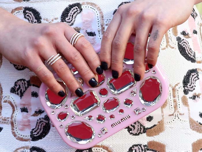 Emilia Clarke carries an embellished Miu Miu clutch