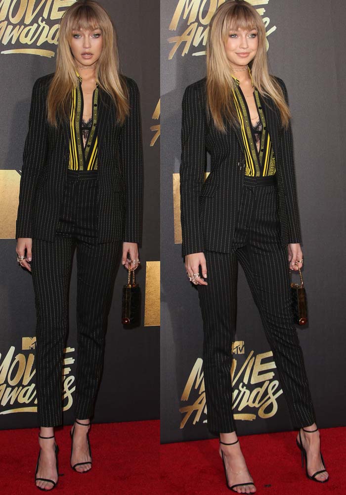 Gigi Hadid wears a pinstriped Versace suit overtop a lacy Anine Bing bra on the red carpet