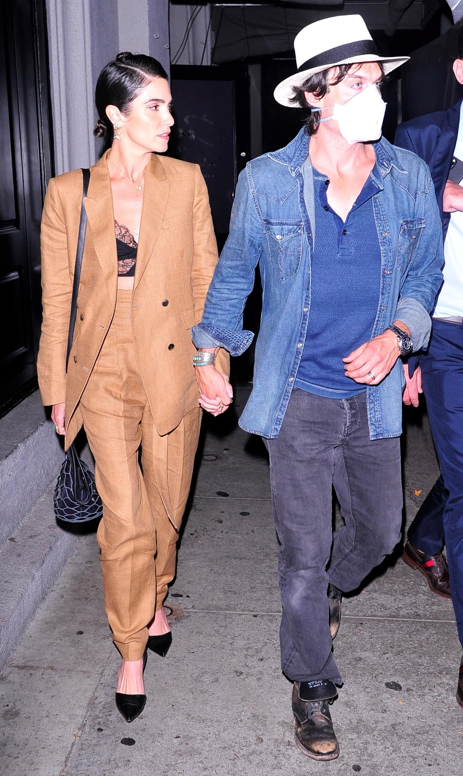 Ian Somerhalder and his wife Nikki Reed hold hands at Craig's after dinner on March 24, 2022, with Nikki donning a chic tan suit paired with black pointed-toe heels and Ian opting for a casual denim shirt, fedora, and rugged boots