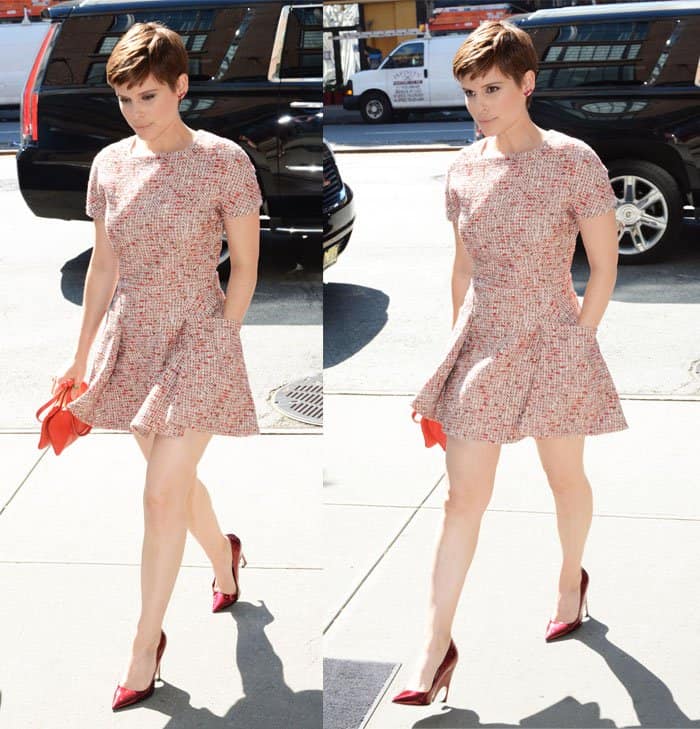 Kate Mara effortlessly embodies a chic and modern look in a textured mini dress, accentuated by bold red heels and a matching clutch, perfect for a daytime outing