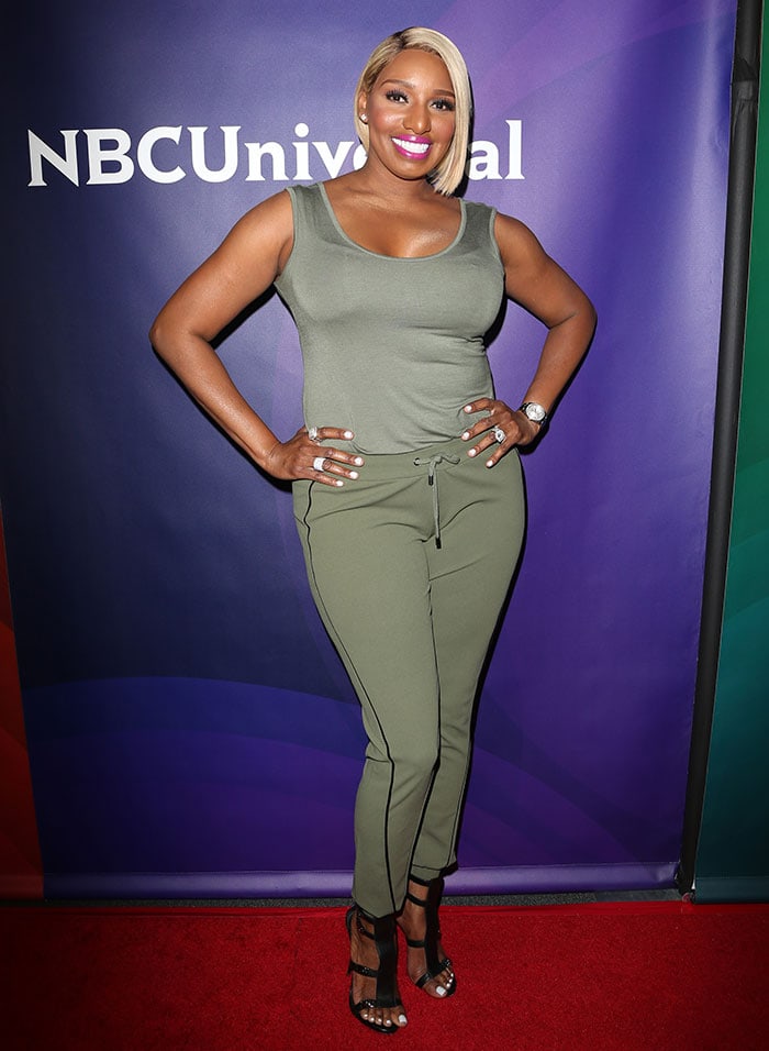 NeNe Leakes rocks the sports-luxe trend with her army green tank top, matching drawstring pants, and chic black strappy heels, blending casual comfort with red carpet glam