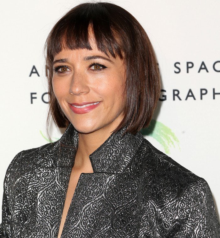 Rashida Jones keeps it chic with a sleek, blunt bob and soft bangs, complementing her glowing skin, winged eyeliner, and glossy pink lips for a polished red carpet look