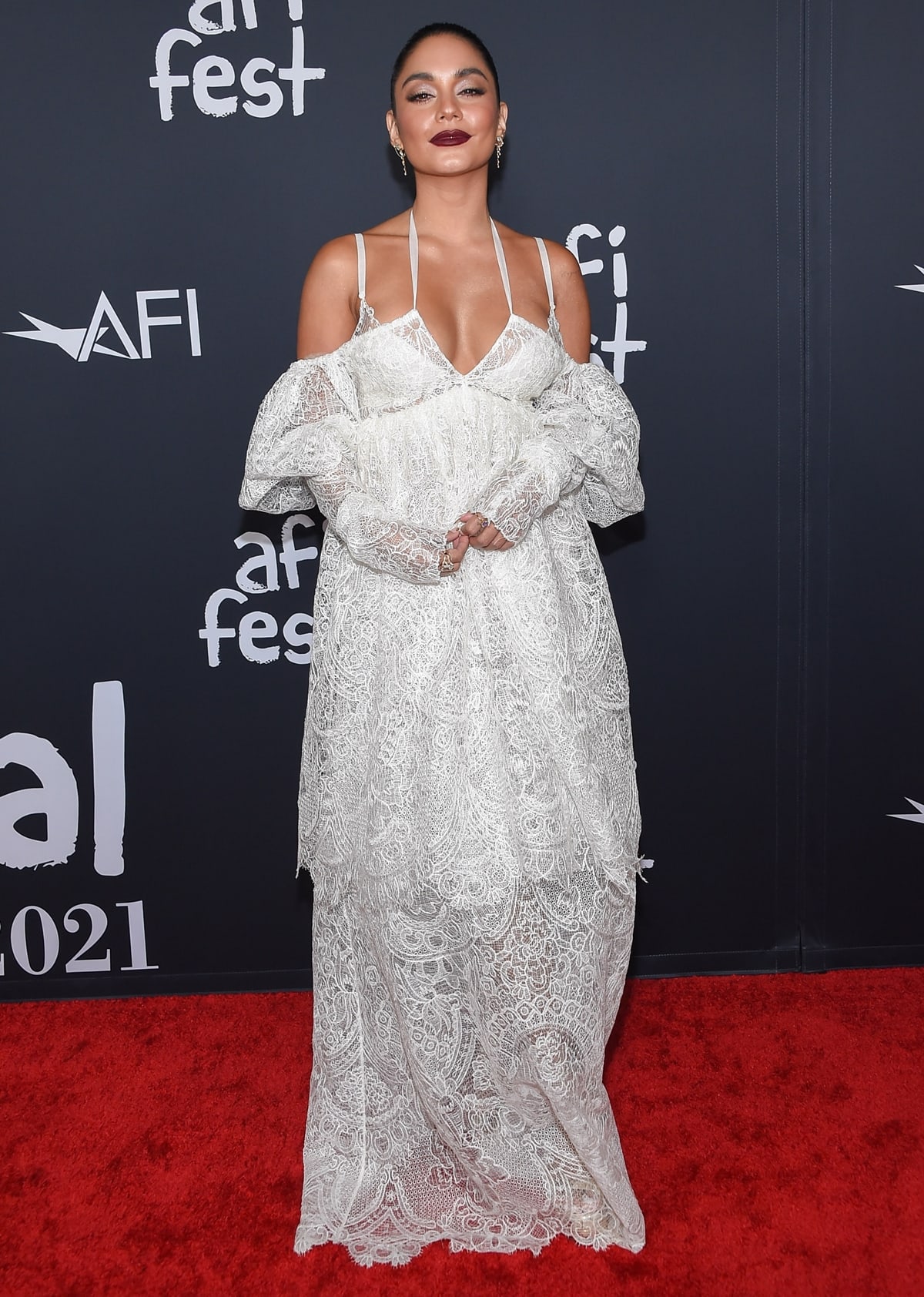 Vanessa Hudgens wears a tiered white lace dress from the Vera Wang Spring 2022 collection and waterfall earrings from SHAY jewelry