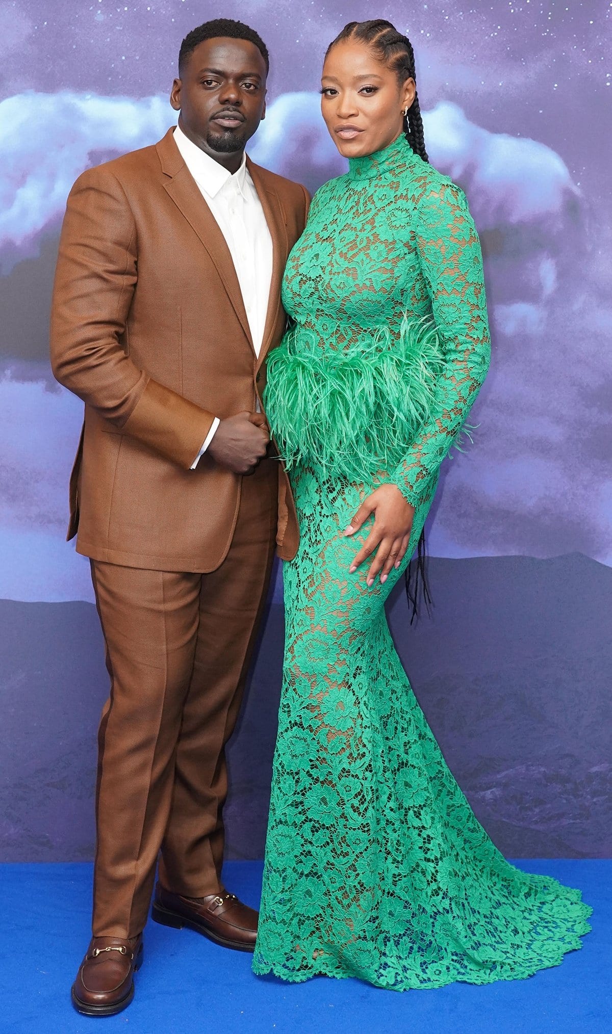Keke Palmer in a green lace Valentino floor-length dress featuring feather boa waist trim poses with Daniel Kaluuya at the UK Premiere Of "NOPE"