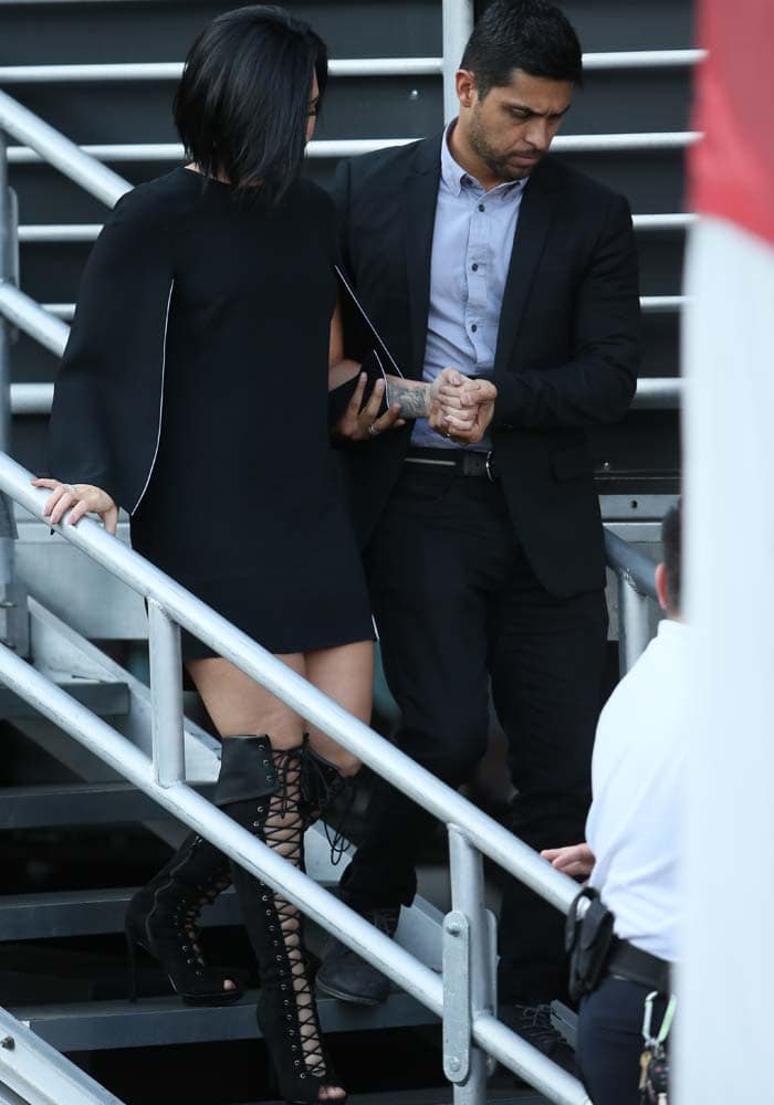 Demi Lovato is escorted by Wilmer Valderrama as she confidently steps out in a chic black mini dress paired with striking lace-up boots