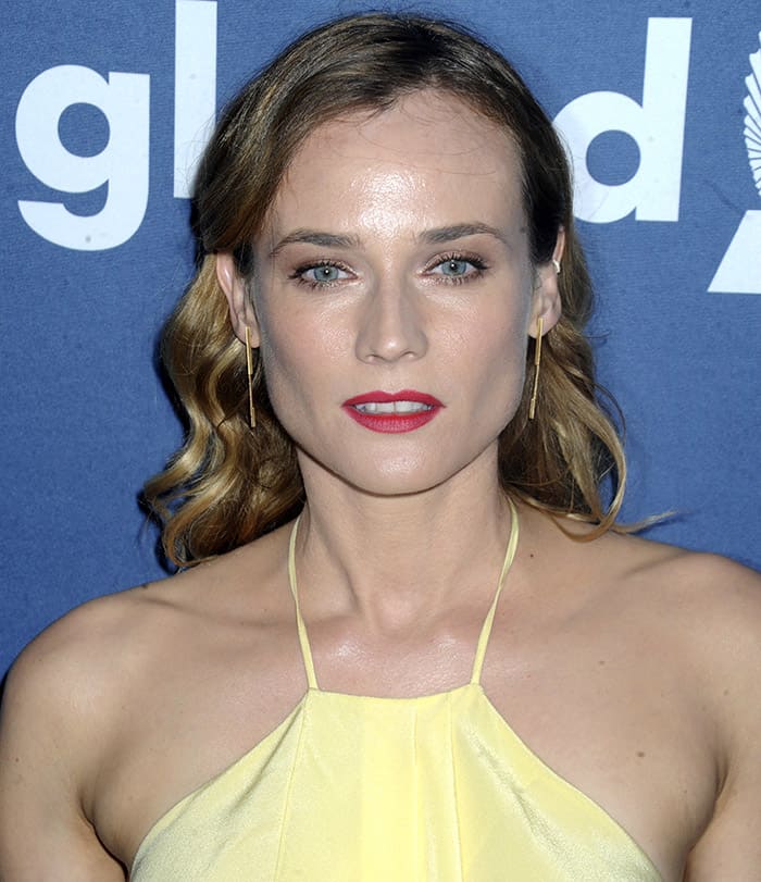 Diane Kruger's hair is styled in soft waves, and she completes the look with a bold red lip