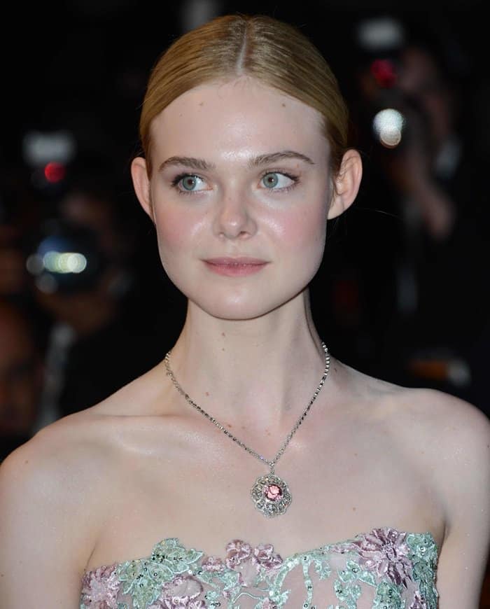 Elevating her allure, a ruby pendant necklace dangled gracefully, drawing attention to Elle Fanning's neckline in an enchanting manner