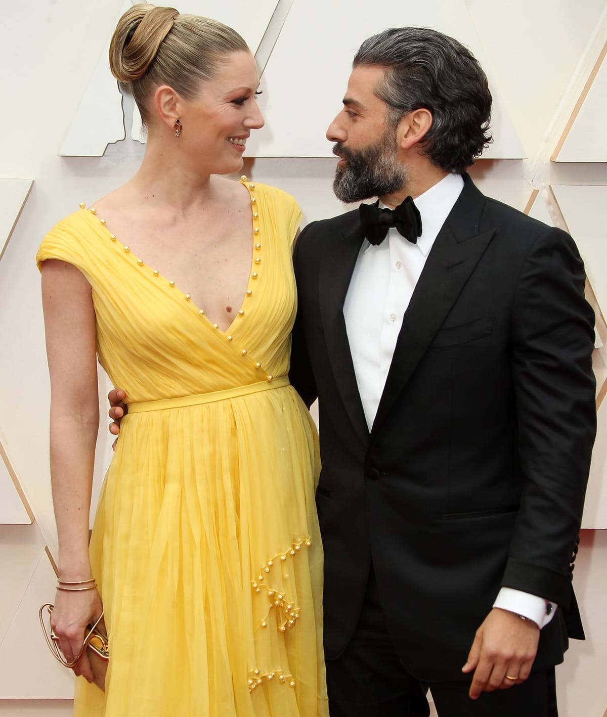 Óscar Isaac and Elvira Lind share a tender moment on the red carpet at the 2020 Academy Awards, with Lind turning heads in a flowing yellow gown embellished with delicate pearls