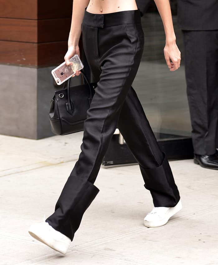 Gigi Hadid gives classic tailored pants a fresh twist by rolling up the hems, pairing them with sleek white sneakers for an effortlessly chic street-style look