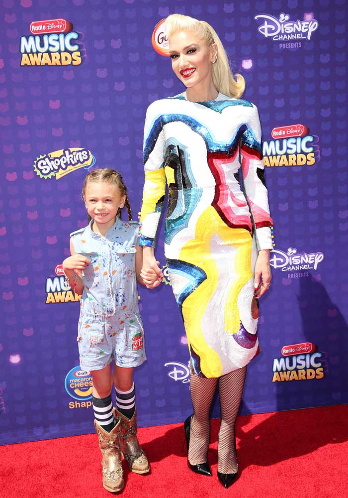 Gwen Stefani holds hands with a child while on the red carpet of the Radio Disney Music Awards