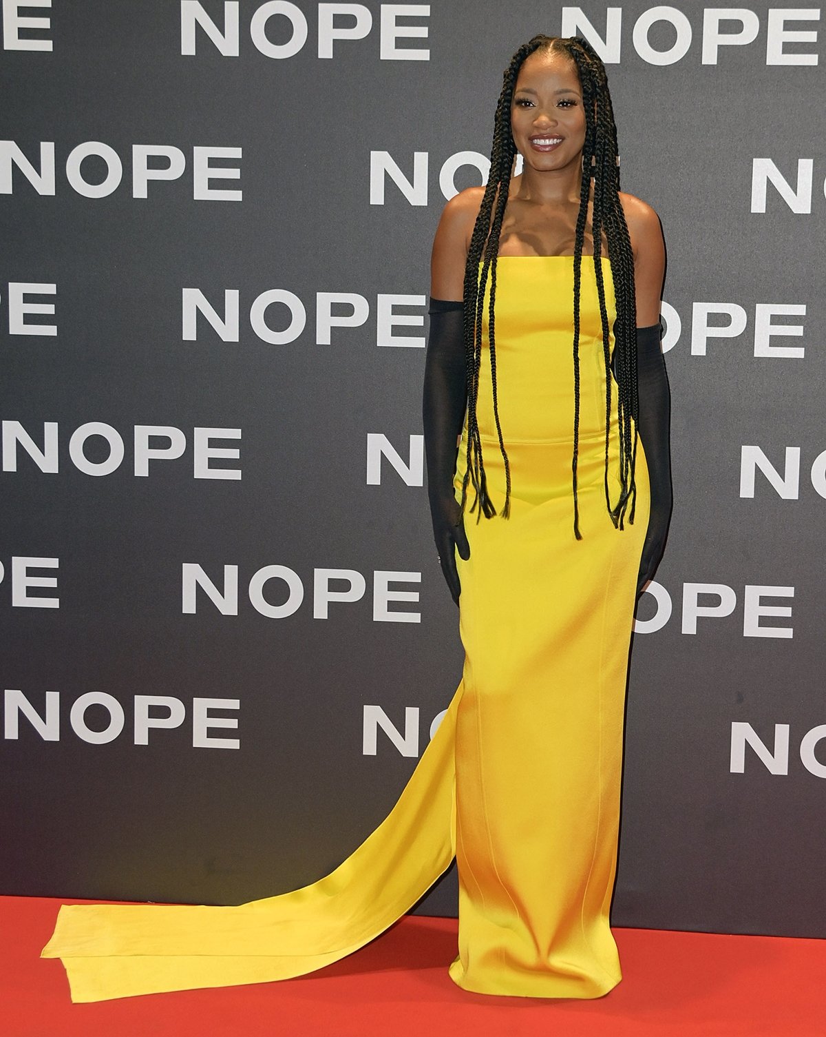 Keke Palmer in a yellow satin Prada dress and long gloves on the red carpet of the Italian premiere Nope