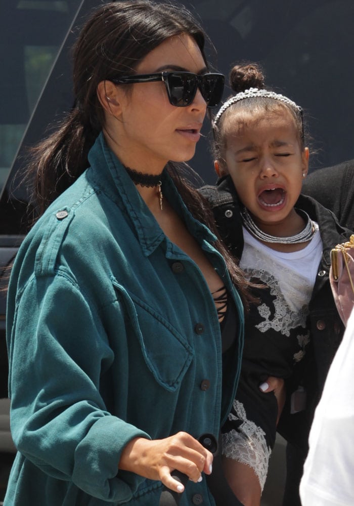 Kim Kardashian carries her crying daughter, North West, on her way to a lunch date with Kanye West and friends Chrissy Teigen and John Legend